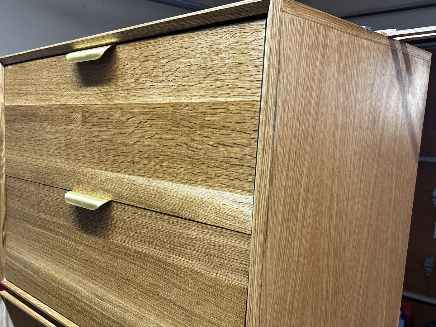 White oak cabinet with flecked drawer fronts and brass edge pulls
