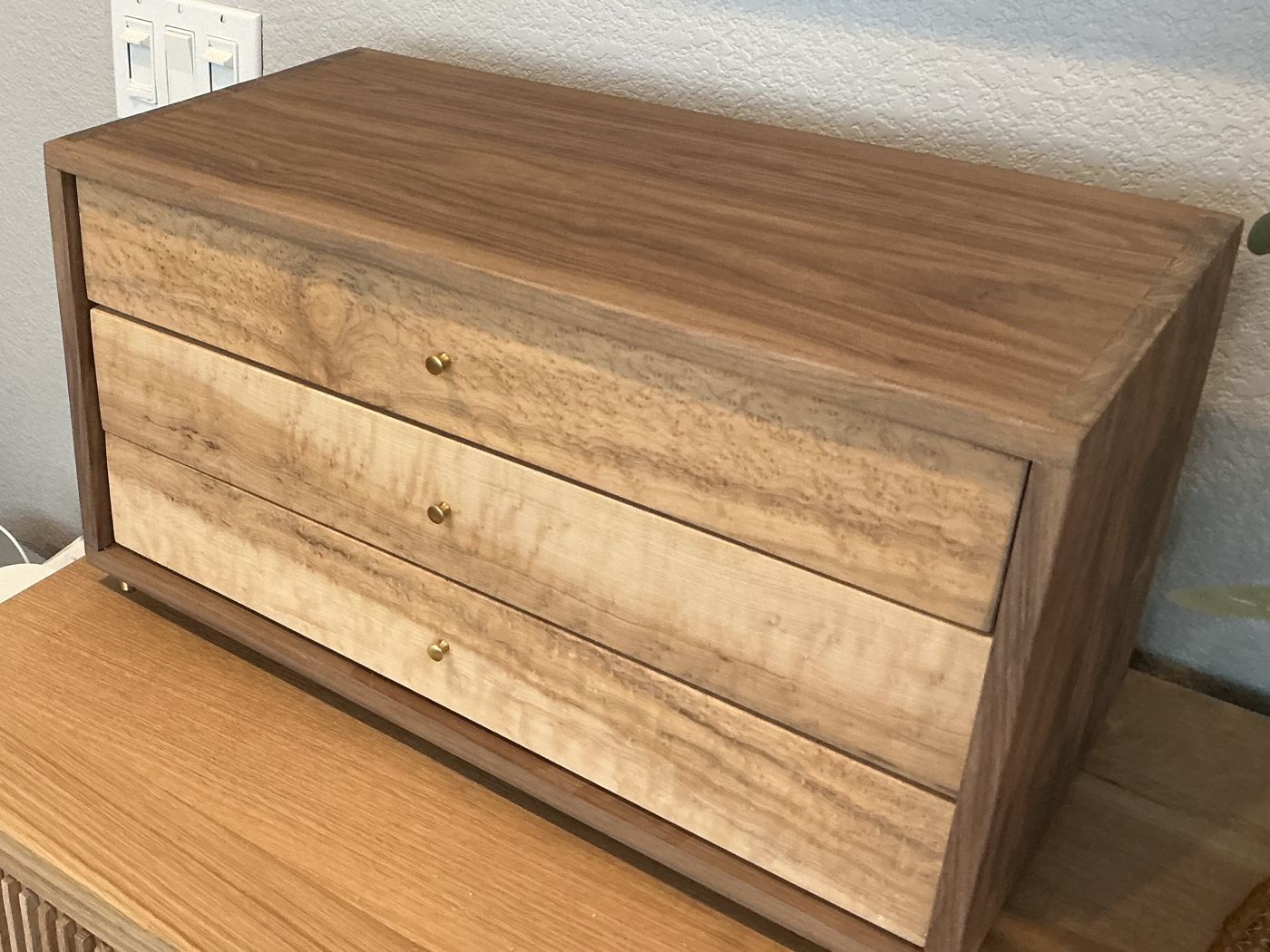 Walnut chest with three figured maple drawers and brass knobs